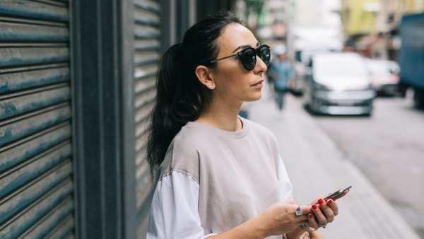 Young woman waiting for taxi in Hong Kong, using smartphone