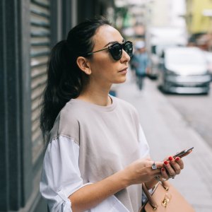 Young woman waiting for taxi in Hong Kong, using smartphone