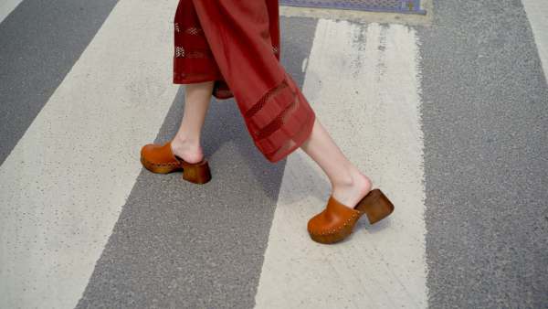 Person wearing red pants and brown clogs walking on a crosswalk. Brussels, Belgium