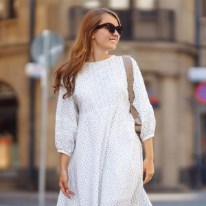 A young woman in a white dress walks through the streets of the city. People, fashion, lifestyle, travel and vacations concept