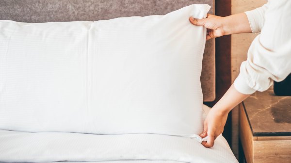 Woman at home making the bed and arranging the pillows.