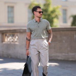 André Hellmundt seen wearing Explicit Poets brown sunglasses, Barbour sage green knit polo shirt, Suit Supply beige long suit pants, Tagheuer silver watch, Furla black leather briefcase / business bag and Bobbie’s Paris brown leather loafers, on August 27, 2024 in Berlin, Germany.