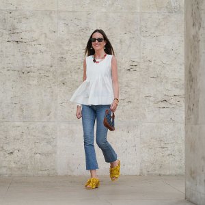 PARIS, FRANCE - MAY 02: Alba Garavito Torre wears black sunglasses, long straight brown hair with a center part, a white pleated peplum sleeveless blouse by Commense, and blue high-rise raw-hem denim jeans. A yellow clog sandal with floral detailing by AGL is worn, paired with a jean denim and brown mini Jackie handbag by Gucci. Accessories include a chunky necklace with colorful natural stones by Sempiterno Paris and gold jewelry. Full body shot, during a street style fashion photo session, on May 02, 2025 in Paris, France. (Photo by Edward Berthelot/Getty Images)