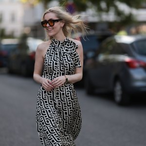 BERLIN, GERMANY - JUNE 19: Lil Paulin is seen wearing oversized black square-framed sunglasses with orange lenses and wide temples, gold hoop earrings, a flowy sleeveless maxi dress with a halter neck and a geometric black and white pattern, a gold rectangular watch from Daniel Wellington, and several filigree silver rings on June 19, 2025 in Berlin, Germany. (Photo by Jeremy Moeller/Getty Images)