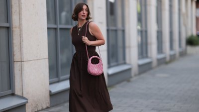 HAMBURG, GERMANY - JULY 18: Franzi Koenig is seen wearing several stud earrings, including gold seashell-shaped studs from fafe collection; layered gold necklaces with a seashell pendant, an F-letter pendant, and a white beaded necklace with a round organic-shaped pendant, also from fafe collection; a sleeveless dark brown midi dress with a ribbed top, high round neckline, and a gathered A-line skirt; a quilted pink leather “Wander” Hobo bag with gold logo hardware and a long thin shoulder strap from Miu Miu; several chunky gold rings, paired with delicate bracelets, both from fafe collection; and dark brown slip-on sandals with kitten heels on July 18, 2025 in Hamburg, Germany. (Photo by Jeremy Moeller/Getty Images)