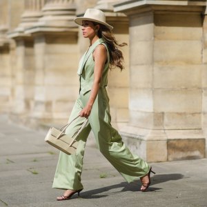 PARIS, FRANCE - MAY 29: Angela Gonzalez wears a beige suede Lack Of Color hat, earrings, a black off shoulder top, a pale green buttoned blazer jacket sleeveless from Nasty Gal, pale green matching Nasty Gal flared pants, a gold chain bracelet, a beige shiny leather Mango handbag, brown shiny leather strappy hells Na-Kd sandals, on May 29, 2021 in Paris, France. (Photo by Edward Berthelot/Getty Images)