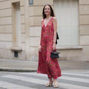 PARIS, FRANCE - JUNE 10: Alba Garavito Torre wears a red Flower print long dress with a tulle collar and black cotton tarsier bow on the neck from Frambua, gold kitten heel sandals, a black mini Kelly bag from Hermes, during a street style fashion photo session, on June 10, 2024 in Paris, France. (Photo by Edward Berthelot/Getty Images)