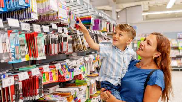 A child excitedly shopping for stationery on his mother's lap