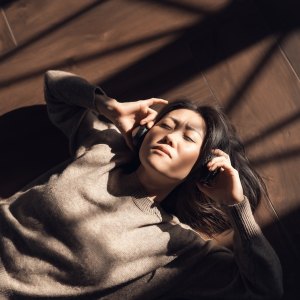 Woman in a brown sweater listening to music