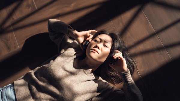 Woman in a brown sweater listening to music