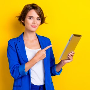 Photo of confident cheerful woman wear blue jacket pointing finger apple samsung modern gadget isolated yellow color background.