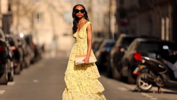 PARIS, FRANCE - MARCH 26: Emilie Joseph @in_fashionwetrust wears black sunglasses, a pale yellow with green and yellow flower print pattern V-neck / tank-top / backless / belted / ruffled maxi long dress, a beige fabric ruffled clutch, silver rings, pale yellow matte leather pointed pumps heels shoes, during a street style fashion photo session, on March 26, 2022 in Paris, France. (Photo by Edward Berthelot/Getty Images)