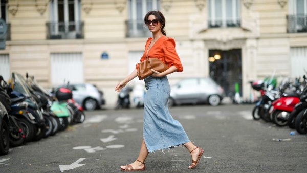 PARIS, FRANCE - AUGUST 28: Ketevan Giorgadze @katie.one wears black and gold chain sunglasses from Art's Sake, gold chain pendant necklaces, gold large earrings, an orange linen cropped / V-neck / puffy sleeves t-shirt from Kao, blue faded denim high waist ripped slit / split midi pencil skirt from Zara, a brown shiny ruffled leather Pouch handbag from Bottega Veneta, gold bracelets, brown shiny leather Santorini sandals from Hermes, on August 28, 2021 in Paris, France. (Photo by Edward Berthelot/Getty Images)