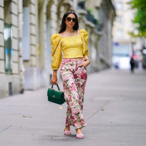 PARIS, FRANCE - JUNE 15: Street style photo session with Gabriella Berdugo wearing Kenzo sunglasses, a yellow ruffled top with puff sleeves and shoulder pads from Avavav, pink Yuulie shoes, a green quilted Chanel bag, pink floral print flared pants from Parosh, a necklace, a watch, on June 15, 2020 in Paris, France. (Photo by Edward Berthelot/Getty Images)