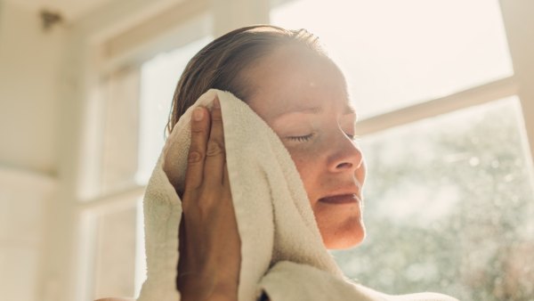 Woman toweling oneself off after bathing in sunny bathroom.