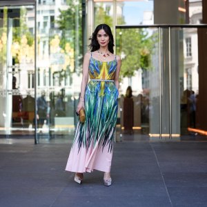 PARIS, FRANCE - JULY 09: Heart Evangelista wears a sleeveless maxi dress featuring a vibrant, multicolored abstract pattern with shades of blue, green, yellow, and pink. The dress has thin straps and a fitted bodice, transitioning into a flowing skirt. A thin belt in a neutral tone cinches the waist. Accessories include a gold-toned clutch with a textured surface and a statement necklace with red accents. Footwear consists of light-colored platform heels. Hair is styled in loose waves, and makeup is subtle with a focus on natural tones, outside Elie Saab, during Paris Fashion Week - Haute Couture Fall/Winter 2025/2026, on July 09, 2025 in Paris, France (Photo by Edward Berthelot/Getty Images)