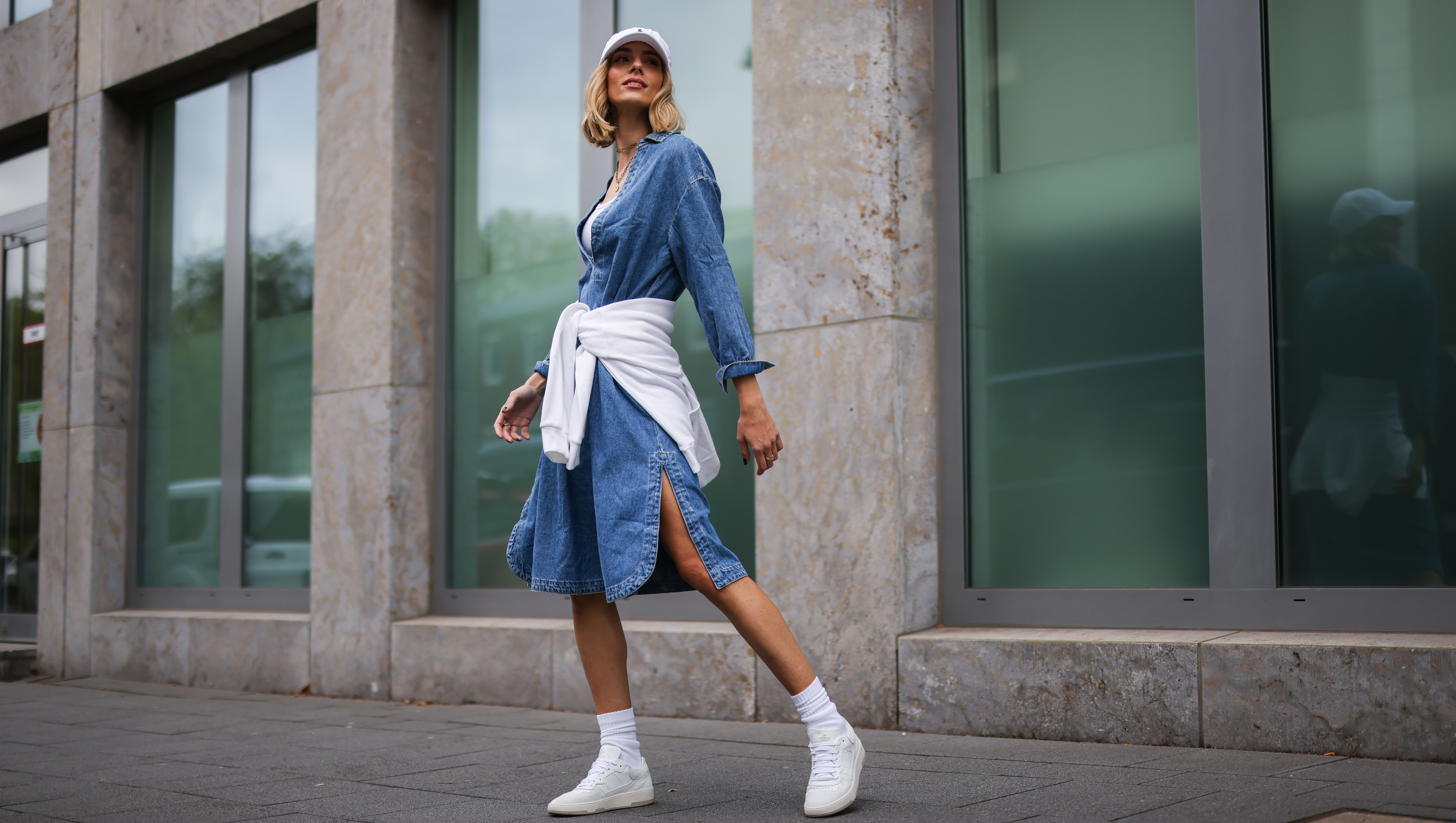 COLOGNE, GERMANY - MAY 11: Justine Schlütter wearing blue denim Mango dress, white ripped Zara tanktop, white Polo Ralph Lauren cap, white Zara hoodie and white Copenhagen Studios sneakers on May 11, 2021 in Cologne, Germany. (Photo by Jeremy Moeller/Getty Images)