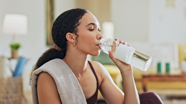 Woman, exercise and drinking water on floor in home with thinking, hydration or liquid for health detox. Girl, person and bottle for workout, nutrition and wellness with training for fitness in house