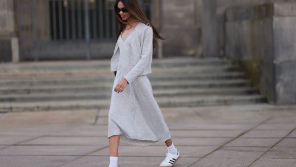 Jill Asemota seen wearing black vintage sunglasses, Dorothee Schumacher grey wool knit long dress, matching Dorothee Schumacher grey wool knit cardigan jacket, white cotton socks, Adidas white leather Samba sneakers, on November 04, 2023 in Berlin, Germany.