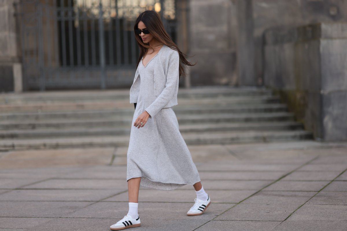 Jill Asemota seen wearing black vintage sunglasses, Dorothee Schumacher grey wool knit long dress, matching Dorothee Schumacher grey wool knit cardigan jacket, white cotton socks, Adidas white leather Samba sneakers, on November 04, 2023 in Berlin, Germany.