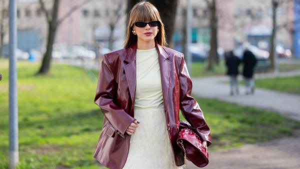 A guest wears burgundy vinyl jacket, beige skirt, pants, shirt, bag outside Jil Sander during the Milan Fashion Week Womenswear Fall/Winter 2025/2026 on February 26, 2025 in Milan, Italy.