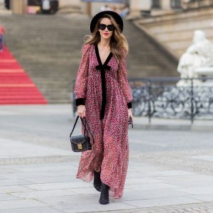 Alexandra Lapp wearing Boho Style, a red and cream floral print maxi dress from Philosophy di Lorenzo Serafini in sheer silk chiffon and bold black trims with a ribbon tie, Toubootfrou ankle boots with rete, organze and suede in black from Christian Louboutin, Celine Audrey sunglasses in black, Maison Maison Michel hat Virginie fedora, MCM Patricia Shoulder Bag in a vintage shape during the Mercedes-Benz Fashion Week Berlin Spring/Summer 2018 on July 7, 2017 in Berlin, Germany.