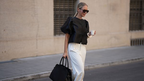 MUNICH, GERMANY - AUGUST 8: Mirja Klein is seen wearing a black short-sleeved Cleo blouse with voluminous puff shoulders and made of glossy material from By Malina; wide-leg off-white trousers with front pleats and elegant design from Rossi; a large structured black leather handbag with double top handles and adjustable straps on the sides from Liviana Conti; oversized aviator sunglasses in brown tortoiseshell acetate with brown shaded lenses from Tom Ford; an ecru colored Luca arm bangle set of two, made of synthetic resin from Sézane; her blonde hair is styled in a sleek low ponytail on August 8, 2025 in Munich, Germany. (Photo by Moritz Scholz/Getty Images)
