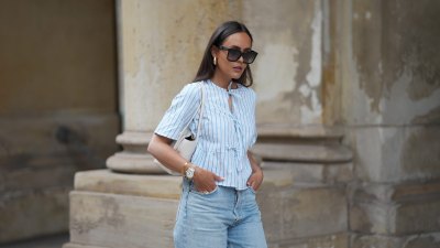 HAMBURG, GERMANY - MAY 7: Laura Noltemeyer is seen wearing a light indigo blue wide leg jeans from Agolde, a cotton puff sleeve blouse with ties in the front in white with blue stripes from Sézane, black oversized cat-eye acetate sunglasses from Celine, Arco handbag in white intrecciato leather from Bottega Veneta, big golden drop-shaped earrings, a small Lady-Datejust watch in gold-silver from Rolex, a golden LOVE bracelet from Cartier, stacked golden rings from Cartier on May 7, 2025 in Hamburg, Germany. (Photo by Moritz Scholz/Getty Images)