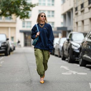 PARIS, FRANCE - NOVEMBER 09: Emy Venturini wears black Rayban sunglasses, a dark blue Supreme sweater, a gold Margiela necklace, a light blue leather Liase bag, khaki wide-leg pants, orange leather Roger Vivier high heels, during a street style fashion photo session, on November 09, 2024 in Paris, France. (Photo by Edward Berthelot/Getty Images)