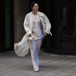 COLOGNE, GERMANY - AUGUST 23: Maria Barteczko seen wearing Ray-Ban gold round retro glasses, Hanro colorful ombré pyjama cotton set, The Frankie Shop cream white transparent lightweight trench coat, LOEWE cream white Flamenco small bag and The Row transparent jelly Mara flat shoes, on August 23, 2024 in Cologne, Germany. (Photo by Jeremy Moeller/Getty Images)