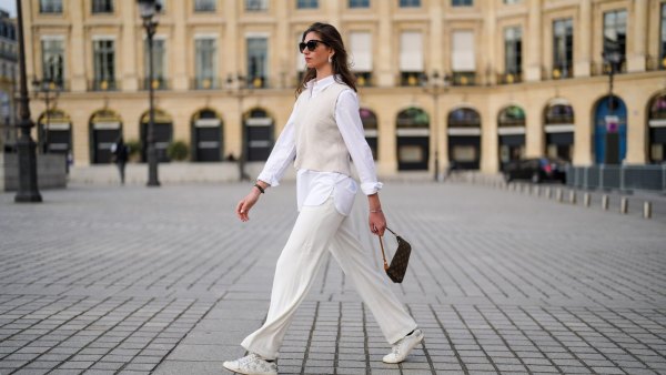 PARIS, FRANCE - APRIL 30: Amanda Derhy @amanda_jashley wears black sunglasses, pearls earrings, an oversized shirt, large flared pants, a beige sleeveless ribs wool pullover, white and silver leather Zadig & Voltaire laces sneakers, silver bracelets, a brown coated canvas monogram Louis Vuitton Lucky Me bracelet, a brown monogram in coated canvas Louis Vuitton Pochette Accessoires shoulder bag, on April 30, 2021 in Paris, France. (Photo by Edward Berthelot/Getty Images)