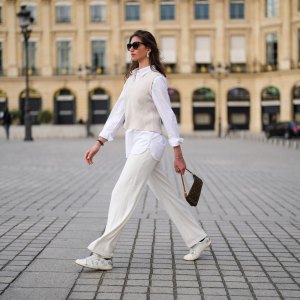 PARIS, FRANCE - APRIL 30: Amanda Derhy @amanda_jashley wears black sunglasses, pearls earrings, an oversized shirt, large flared pants, a beige sleeveless ribs wool pullover, white and silver leather Zadig & Voltaire laces sneakers, silver bracelets, a brown coated canvas monogram Louis Vuitton Lucky Me bracelet, a brown monogram in coated canvas Louis Vuitton Pochette Accessoires shoulder bag, on April 30, 2021 in Paris, France. (Photo by Edward Berthelot/Getty Images)