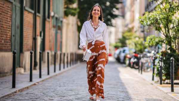 PARIS, FRANCE - JULY 17: Alba Garavito Torre wears a necklace with white large pearls, a white shirt closed with a knot from Ralph Lauren, a brown and white striped tie and dye printed lustrous silky skirt from Imprevu Belgium, white Hermes Oasis sandals, a white Jacquemus bag, on July 17, 2021 in Paris, France. (Photo by Edward Berthelot/Getty Images)