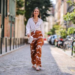 PARIS, FRANCE - JULY 17: Alba Garavito Torre wears a necklace with white large pearls, a white shirt closed with a knot from Ralph Lauren, a brown and white striped tie and dye printed lustrous silky skirt from Imprevu Belgium, white Hermes Oasis sandals, a white Jacquemus bag, on July 17, 2021 in Paris, France. (Photo by Edward Berthelot/Getty Images)