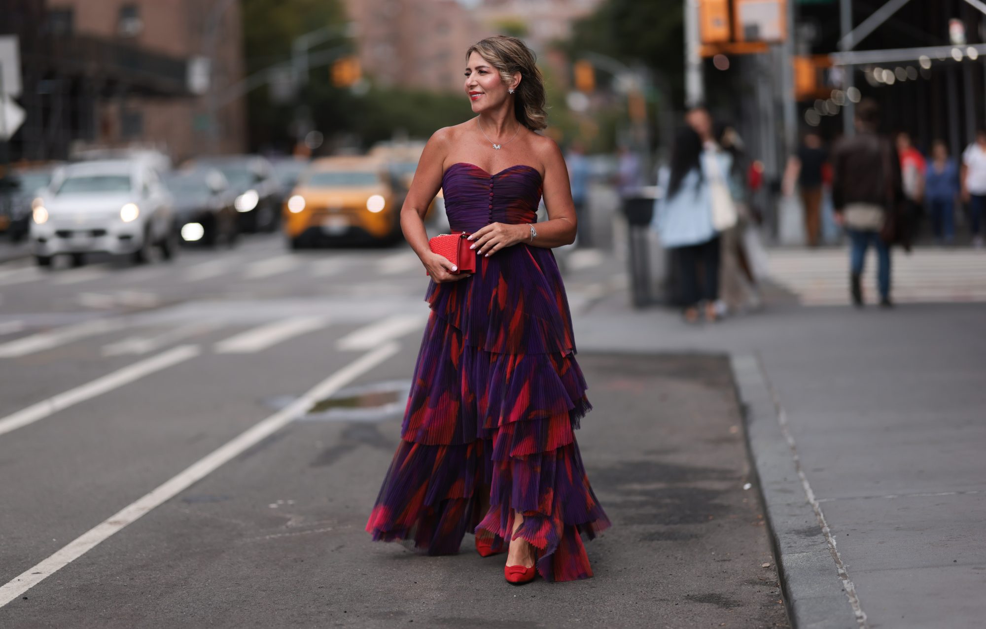 NEW YORK, NEW YORK - SEPTEMBER 07: Olga Ferrara seen wearing Leibish diamond necklace / diamond earrings / diamond bracelet, Hutch pink / purple pattern bandeau pleated long dress, Emanuel Ungaro red leather clutch bag and Scarlett Chase red suede leather pumps / heels, on September 07, 2024 in New York City. (Photo by Jeremy Moeller/Getty Images)