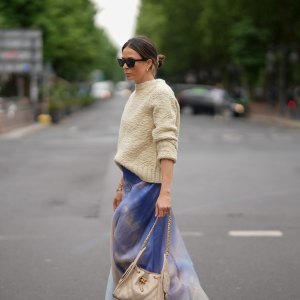 DUSSELDORF, GERMANY - MAY 27: Patricia Wirschke is seen wearing a blue printed silk-organza maxi skirt from Zimmermann, a cream white wool knit sweater with straight fit and round neckline from Jil Sander, brown cat-eye sunglasses with tortoiseshell finish from Celine, a beige small calfskin Chanel 25 hobo handbag with golden hardware and chain and logo details from Chanel, yellow golden Serpenti Viper hoop earrings with snake-like design from Bvlgari, a golden Juste un Clou bracelet from Cartier, a yellow golden Serpenti Viper bracelet with snake-like design from Bvlgari, a yellow golden Love bracelet from Cartier, a silver diamond ring on May 27, 2025 in Dusseldorf, Germany. (Photo by Moritz Scholz/Getty Images)