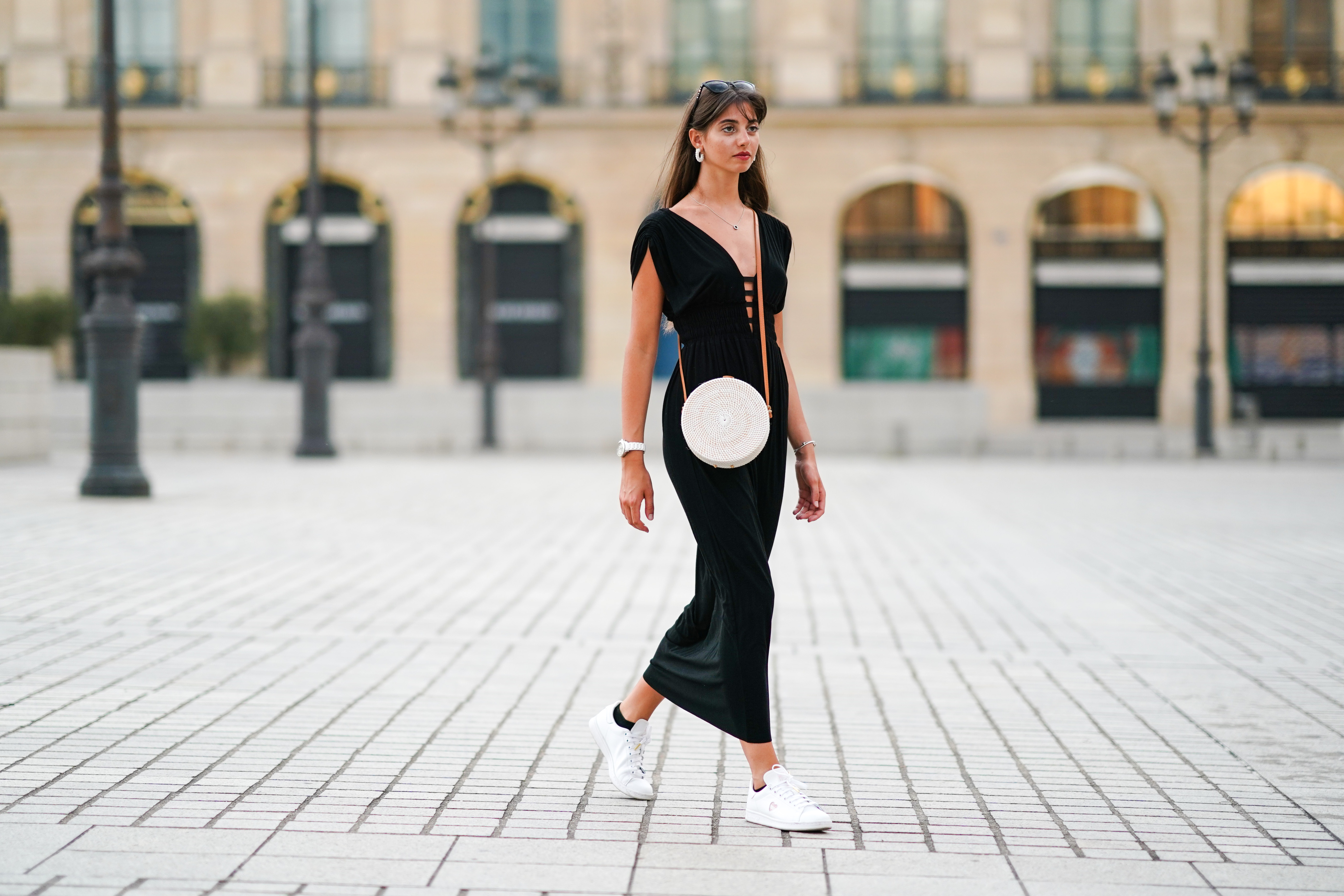 PARIS, FRANCE - AUGUST 09: Amanda Derhy wears earrings, a black low-neck v-neck dress, a white circular round straw summer bag, a watch, white Adidas sneakers shoes, on August 09, 2020 in Paris, France. (Photo by Edward Berthelot/Getty Images)