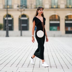 PARIS, FRANCE - AUGUST 09: Amanda Derhy wears earrings, a black low-neck v-neck dress, a white circular round straw summer bag, a watch, white Adidas sneakers shoes, on August 09, 2020 in Paris, France. (Photo by Edward Berthelot/Getty Images)