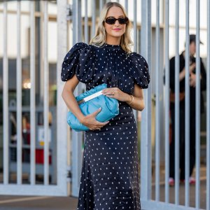 A guest seen wearing navy polka dot dress, blue bag, white sandals outside Munthe during Copenhagen Fashion Week Spring/Summer 2023 on August 11, 2022 in Copenhagen, Denmark.