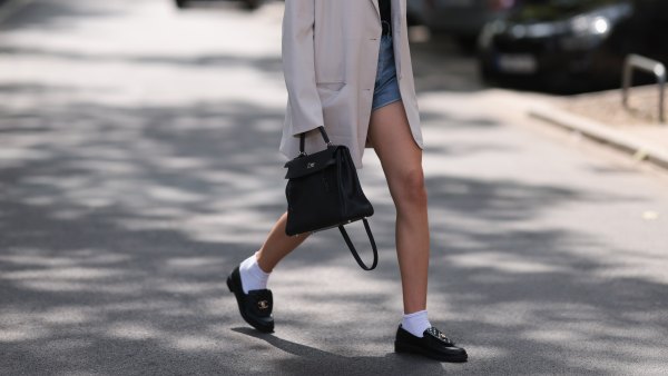 DUSSELDORF, GERMANY - JULY 14: Isabelle Hartmann is seen wearing black narrow sunglasses from Saint Laurent, an oversize beige blazer from The Frankie Shop, underneath a black top from Massimo Dutti, high-waisted jeans shorts from Agolde with a black leather vintage belt, golden rings, the Kelly bag from Hermes in black leather, white socks and black leather loafers from Chanel on July 22, 2023 in Dusseldorf, Germany. (Photo by Jeremy Moeller/Getty Images)