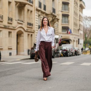 PARIS, FRANCE - DECEMBER 18: Alba Garavito Torre wears a white Figaret shirt, dark brown wide-leg Prassos pants, a brown Tras mi Bolsa bag with leopard patterns, tobacco heels slingback penny loafers from Miu Miu, during a street style fashion photo session, on December 18, 2024 in Paris, France. (Photo by Edward Berthelot/Getty Images)