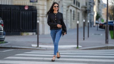 Patricia Gloria Conteras wears black and white sunglasses, silver Chanel earrings, a pearl necklace, a black jacket with gold buttons, blue denim jeans / pants, a black leather bag, black leather ballerinas shoes, during a street style fashion photo session, on January 07, 2025 in Paris, France.