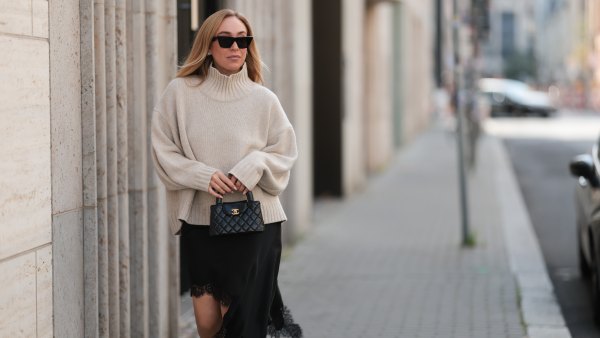 BERLIN, GERMANY - AUGUST 20: Sonia Lyson seen wearing Celine black cat-eye sunglasses, COS relaxed oversized beige turtleneck sweater in a chunky knit with dropped shoulders, Zara black asymmetrical slip dress featuring delicate lace trim along the hem and Chanel small black quilted top-handle Kelly bag with gold CC logo hardware, on August 20, 2025 in Berlin, Germany. (Photo by Jeremy Moeller/Getty Images)