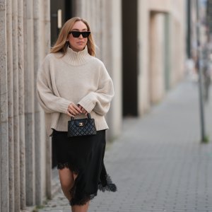 BERLIN, GERMANY - AUGUST 20: Sonia Lyson seen wearing Celine black cat-eye sunglasses, COS relaxed oversized beige turtleneck sweater in a chunky knit with dropped shoulders, Zara black asymmetrical slip dress featuring delicate lace trim along the hem and Chanel small black quilted top-handle Kelly bag with gold CC logo hardware, on August 20, 2025 in Berlin, Germany. (Photo by Jeremy Moeller/Getty Images)