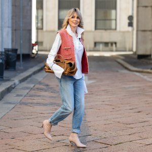 MILAN, ITALY - SEPTEMBER 28: Ekaterina Mamaeva wears white shirt Anna Quan, red vest Chanel, jeans Saint Laurent, rose ankle boots Acne Studios, brown bag Khaite during the Milan Fashion Week Womenswear Spring/Summer 2026 on September 28, 2025 in Milan, Italy. (Photo by Christian Vierig/Getty Images)