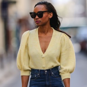 PARIS, FRANCE - APRIL 03: Emilie Joseph @in_fashionwetrust wears sunglasses, pale pastel yellow a puffed sleeves wool cardigan from Mango, high rise blue denim jeans pants from Levi's, on April 03, 2021 in Paris, France. (Photo by Edward Berthelot/Getty Images)