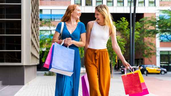 Cheerful friends walking with shopping bags outside shopping mall - stock photo