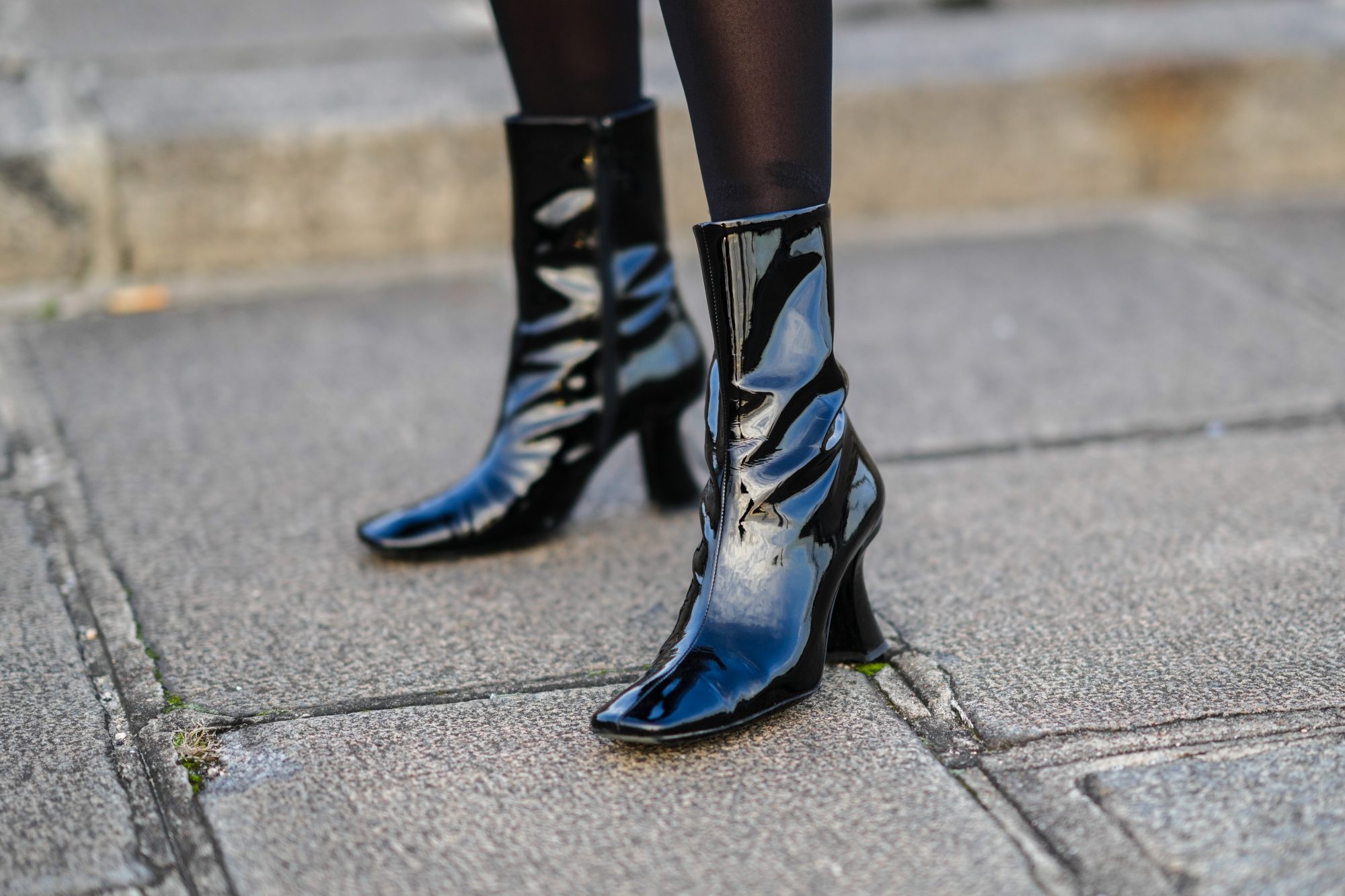 PARIS, FRANCE - DECEMBER 11: Emilie Joseph @in_fashionwetrust wears black tights, black shiny leather / vinyle heels ankle boots with square toe-cap, during a street style fashion photo session, on December 11, 2021 in Paris, France. (Photo by Edward Berthelot/Getty Images)