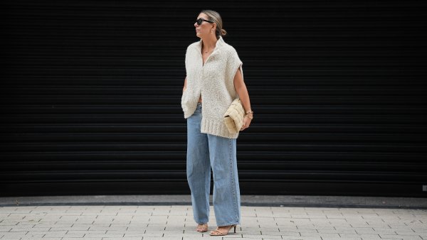 HAMBURG, GERMANY - SEPTEMBER 19: Aylin König is seen wearing a loose, chunky knit sleeveless, zip-up sweater in a soft beige tone with a wide collar and relaxed drape; light blue straight-leg jeans with a slightly wide fit; nude strappy heeled sandals; a beige woven-style clutch bag with a padded texture; stacked gold bracelets from Cartier; a watch with a metallic wristband and white clock face from Cartier; gold detailed rings; gold link earrings from Tiffany & Co HardWear Collection; black rectangular sunglasses; her dark hair is pulled back into a neat, low bun on September 19, 2025 in Hamburg, Germany. (Photo by Moritz Scholz/Getty Images)