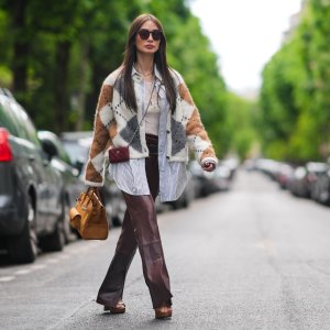 PARIS, FRANCE - APRIL 27: Heart Evangelista wears sunglasses, a golden necklace, a gray brown and white wool cardigan with checked patterns, a white t-shirt from Saint-Laurent YSL, a belt, burgundy slit leather pants , a burgundy leather mini quilted Chanel bag, an orange / brown large Hermes bag, brown shoes, during a street style fashion photo session, on April 27, 2024 in Paris, France. (Photo by Edward Berthelot/Getty Images)